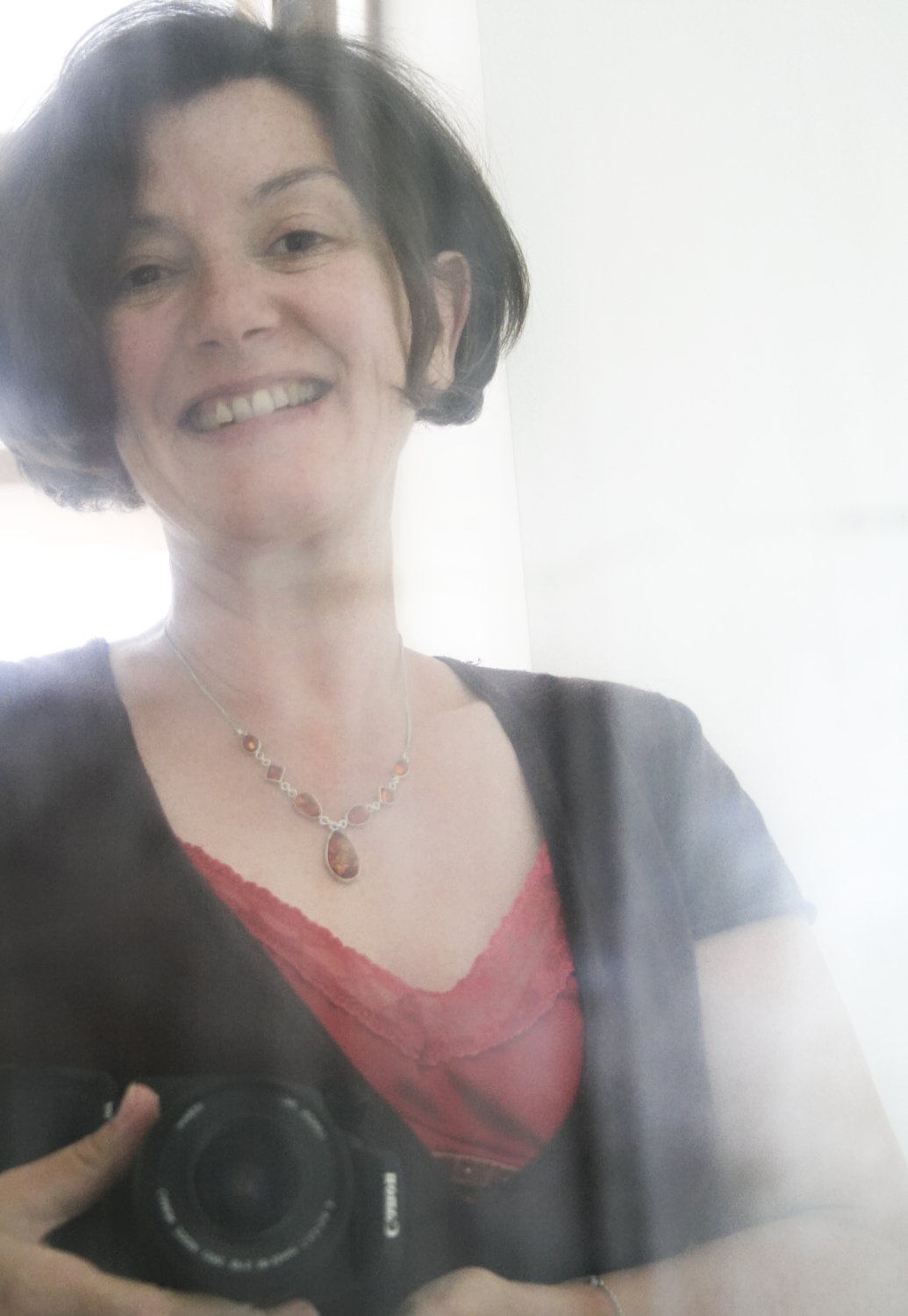 Autoportrait au corsage rouge. Luce, Via Tara Autoportrait de Luce Dupont de Luce Dupont devant un miroir. Photographe des femmes, elle pose avac son appareil photo